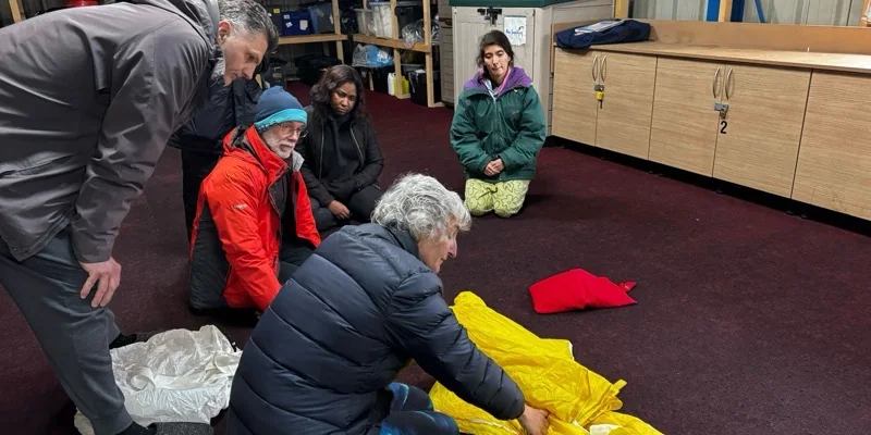 A packing class kneeling around a yellow canopy being flaked on the floor